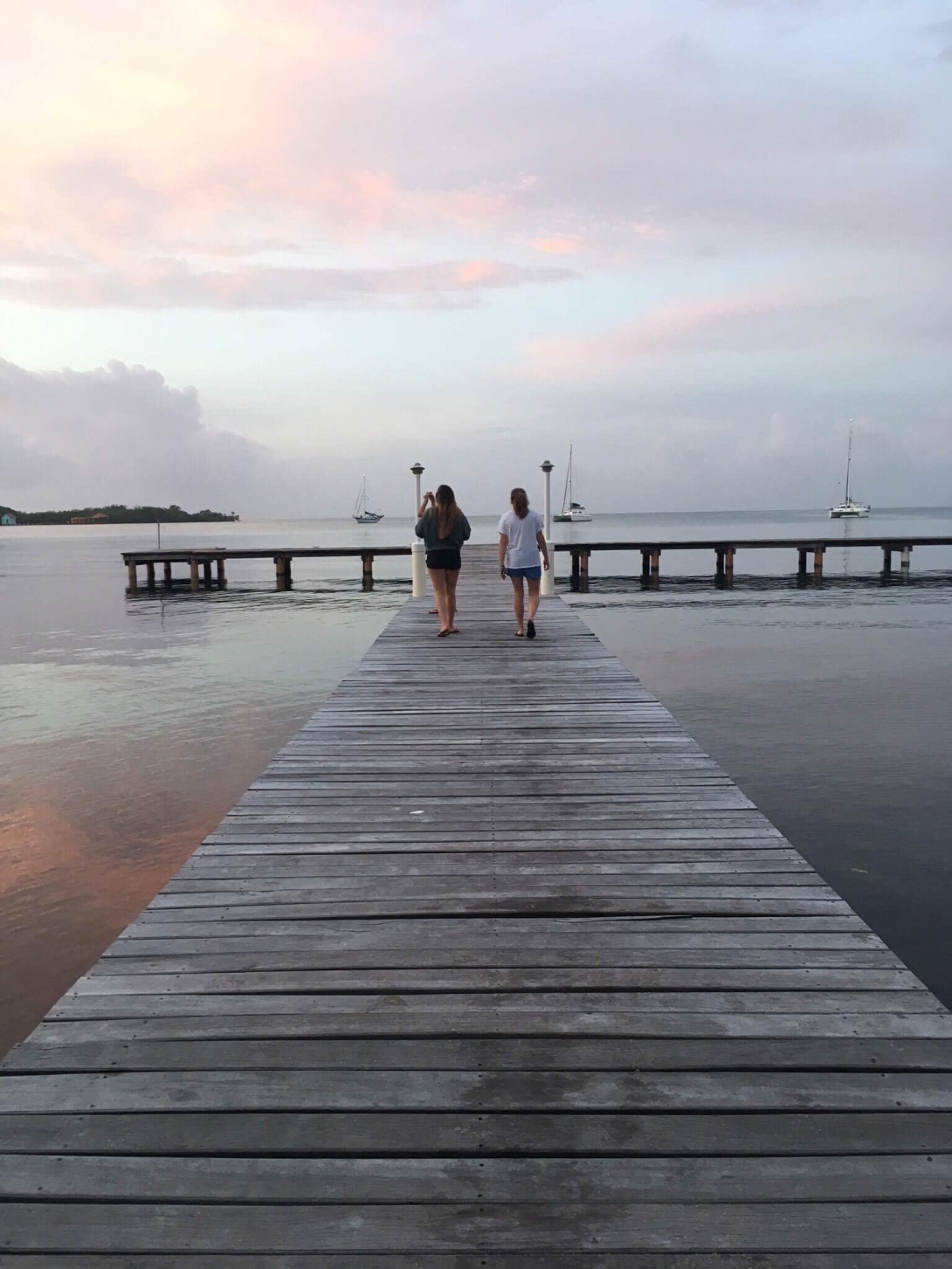 Conservation group volunteers in Belize enjoying scenery from a dock Projects Abroad marine conservation group volunteers walking down a dock